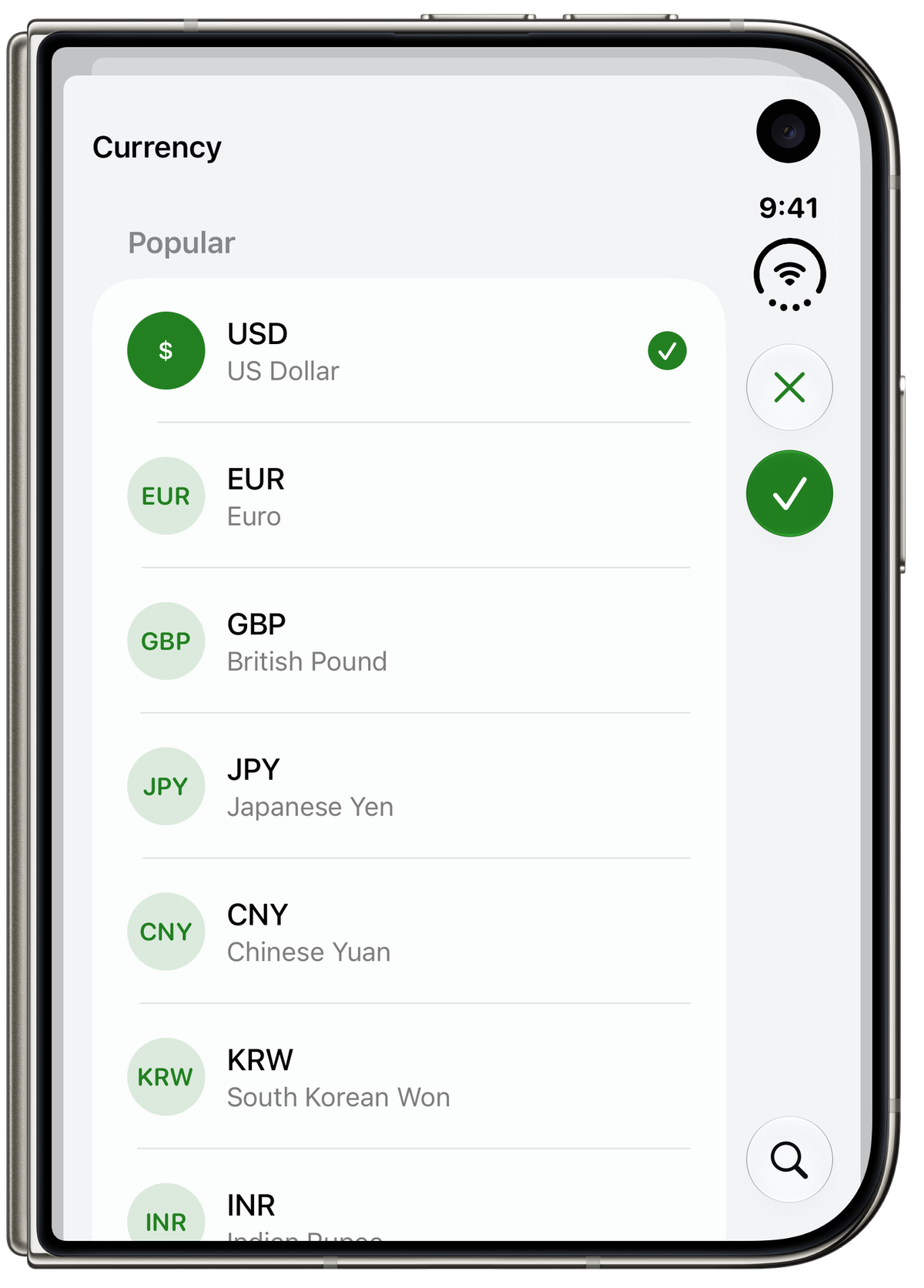iPhone Duo folded, showing Elavo's Currency screen on the cover display with a list of popular currencies (USD selected, EUR, GBP, JPY, CNY, KRW, INR) and close, confirm and search buttons along the right edge.